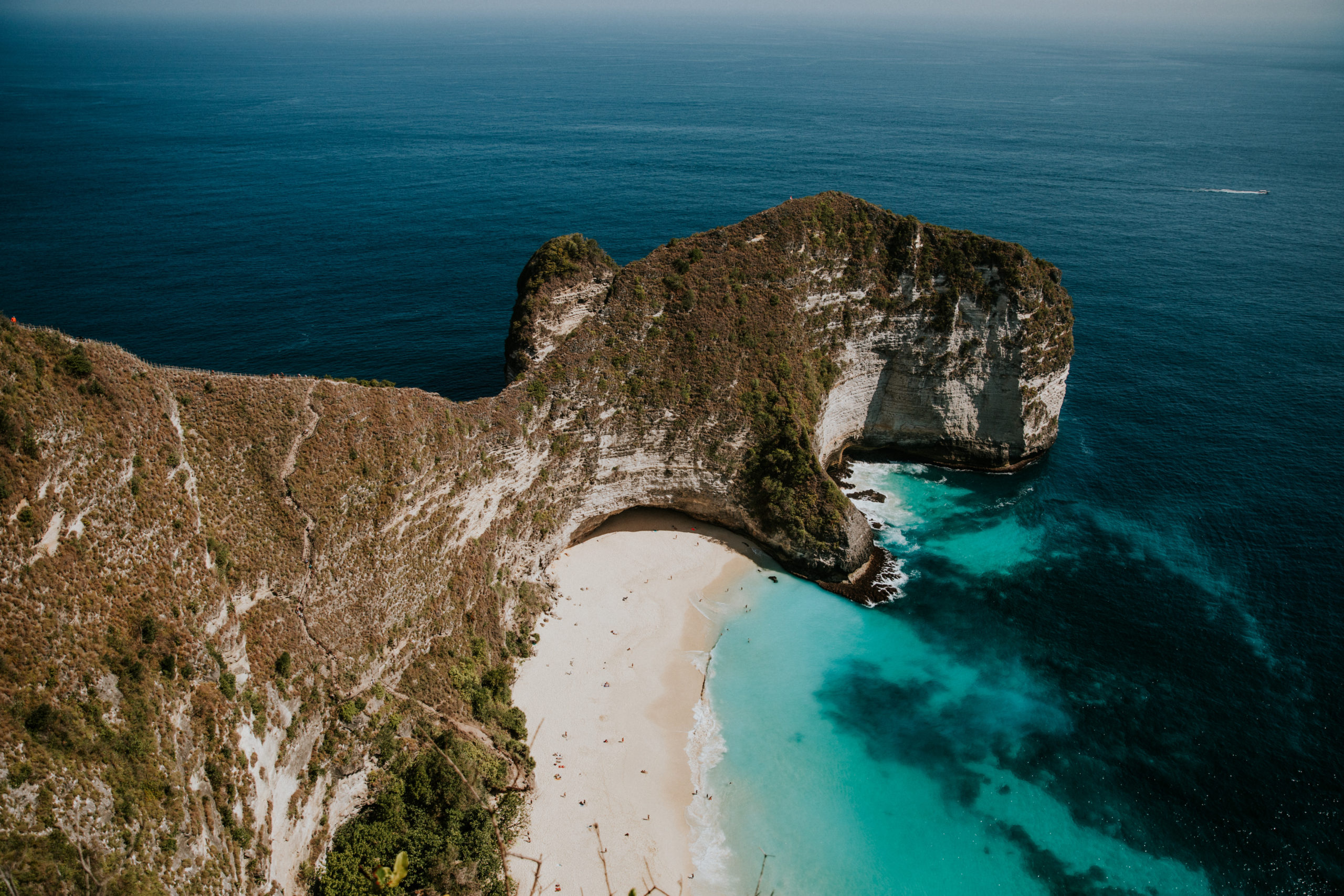 cliff with blue water and white sand beach